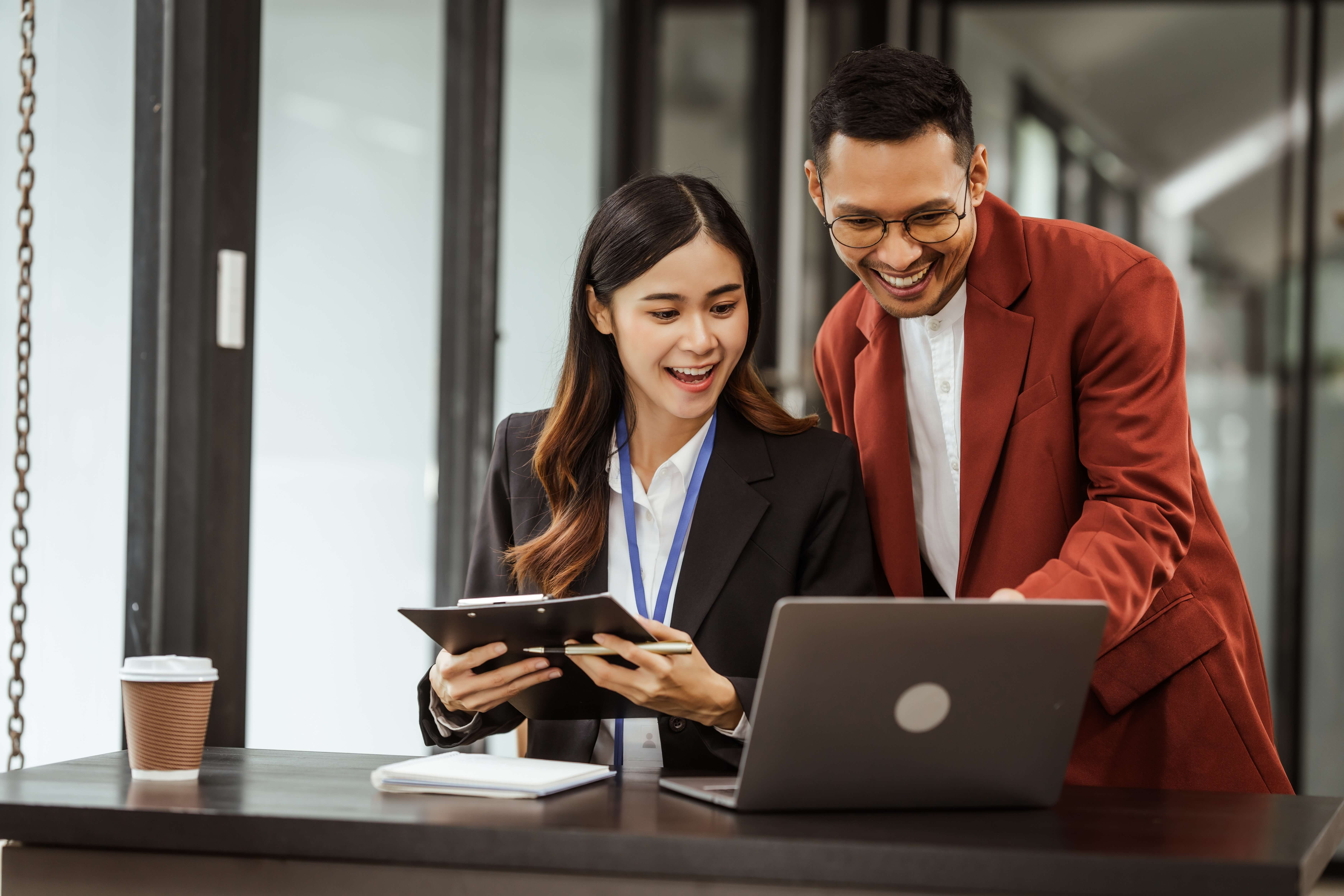 two office workers smiling at laptop