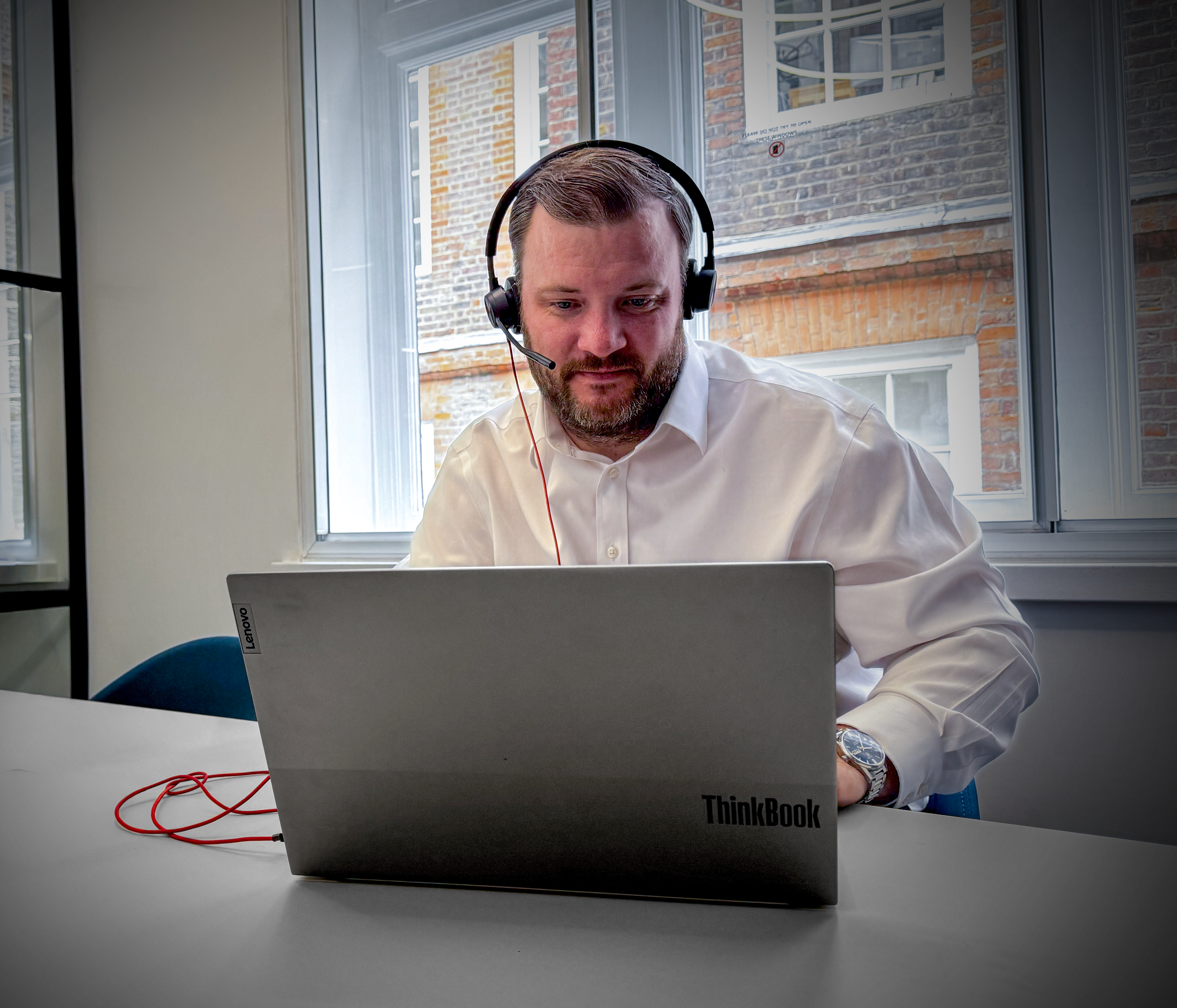 male accountant wearing headset speaking on laptop